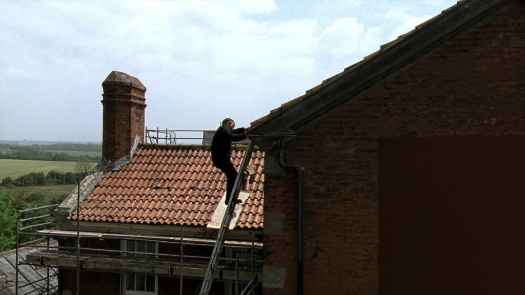 Roofer on a ladder working on an orange clay tiled roof beside a brick chimney, with scaffolding at the eaves